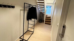 A hallway with a shoe rack, a black mat, and a staircase leading to an upper level. - Sentrumsnær leilighet med 5 soverom - Montis (Tromsø)