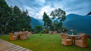 An outdoor seating area with wicker furniture and a view of mountains. - Udaan Yalley Resort & Spa Gangtok (Gangtok)