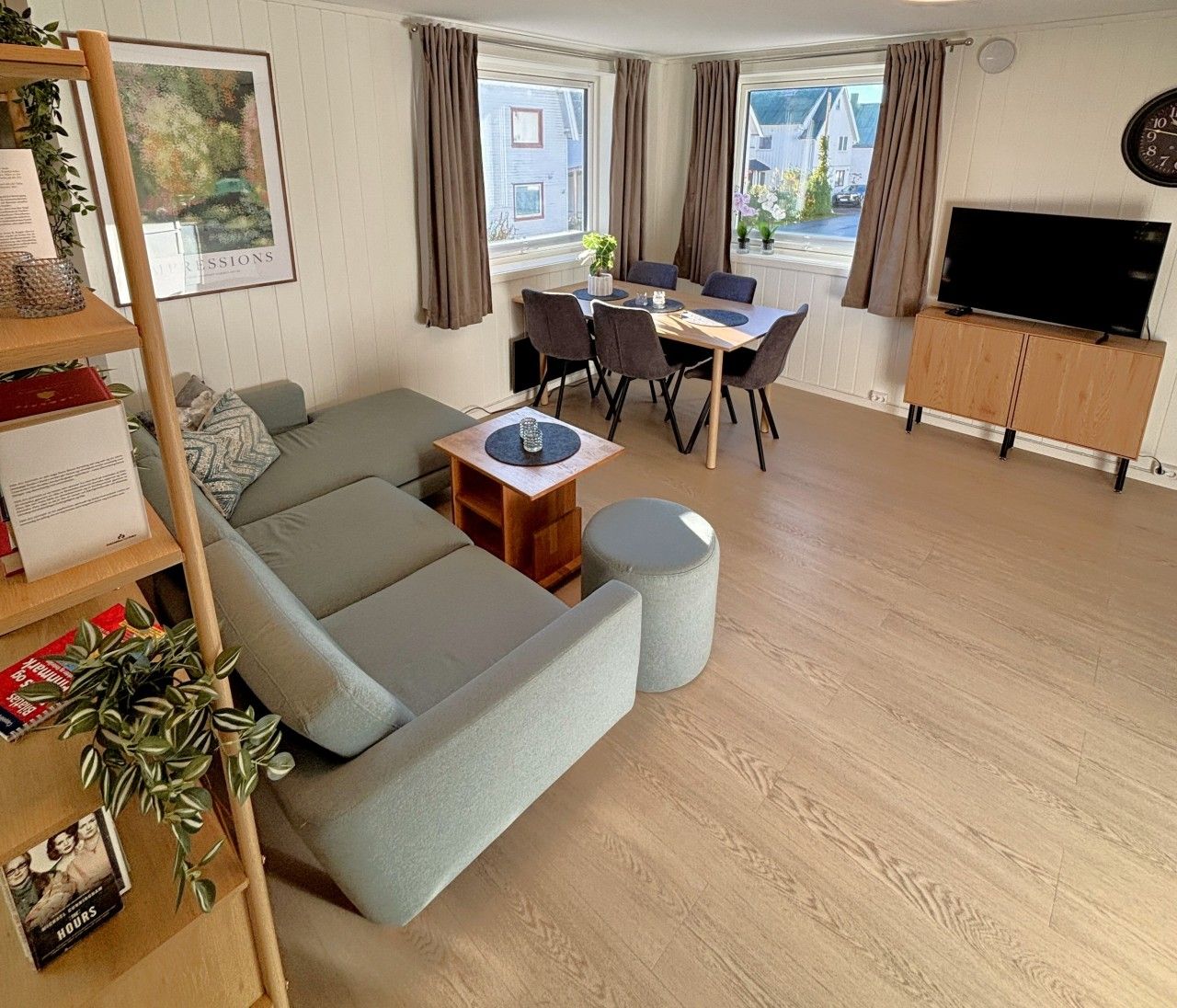 Een woonkamer met een bank, voetenbankje, salontafel, en een eethoek met stoelen en een tafel.