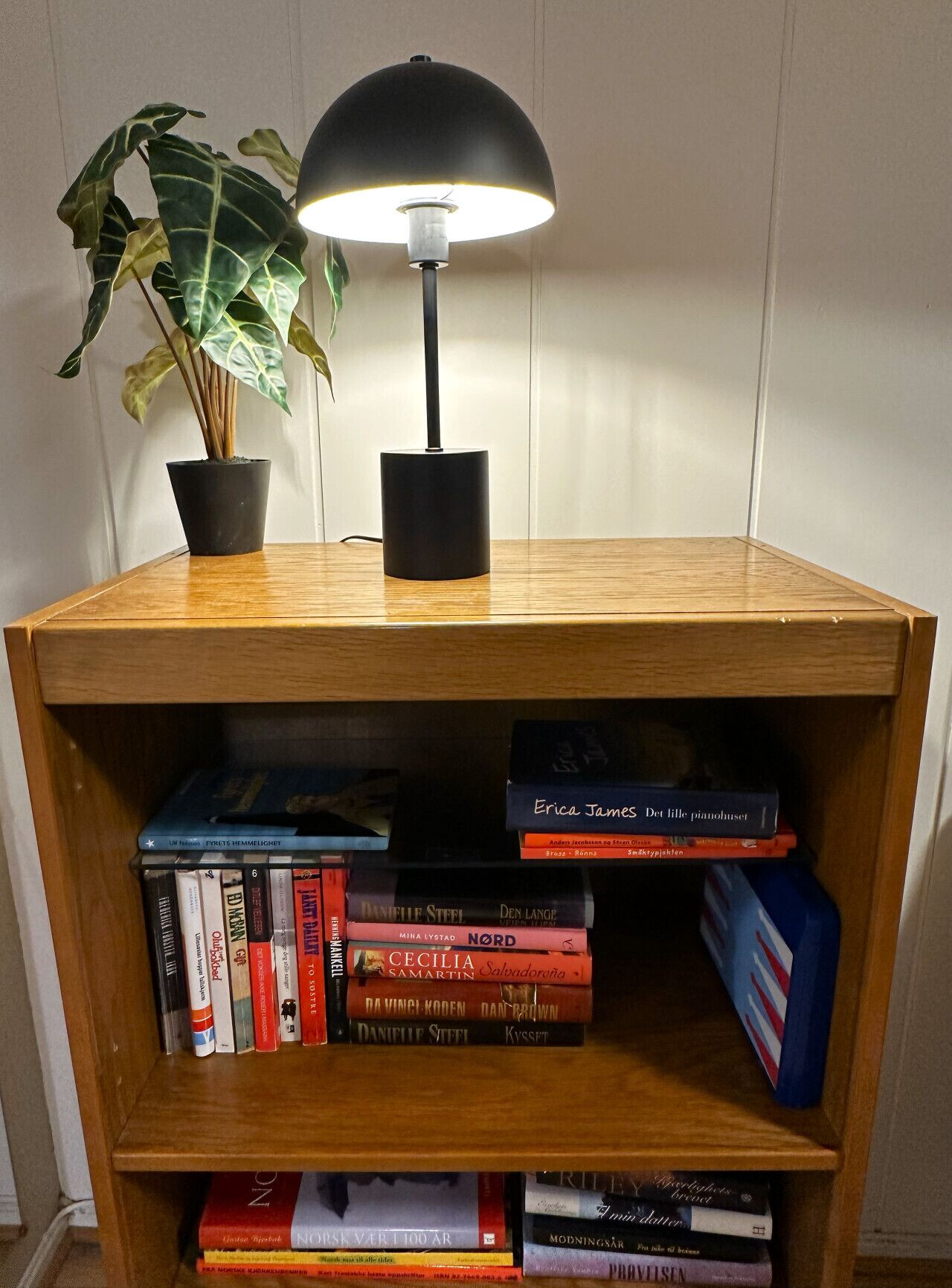 En reol med bøger og en lampe.