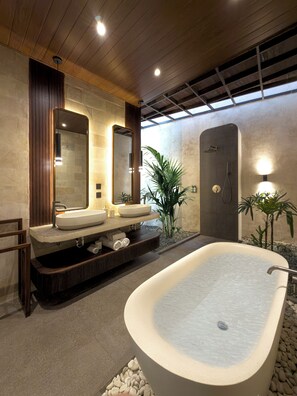 A modern bathroom with a freestanding bathtub, two sinks, and a large mirror.