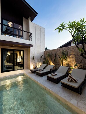 A modern house with a swimming pool, lounge chairs, and a stone wall. - Eden Villas (Kuta)