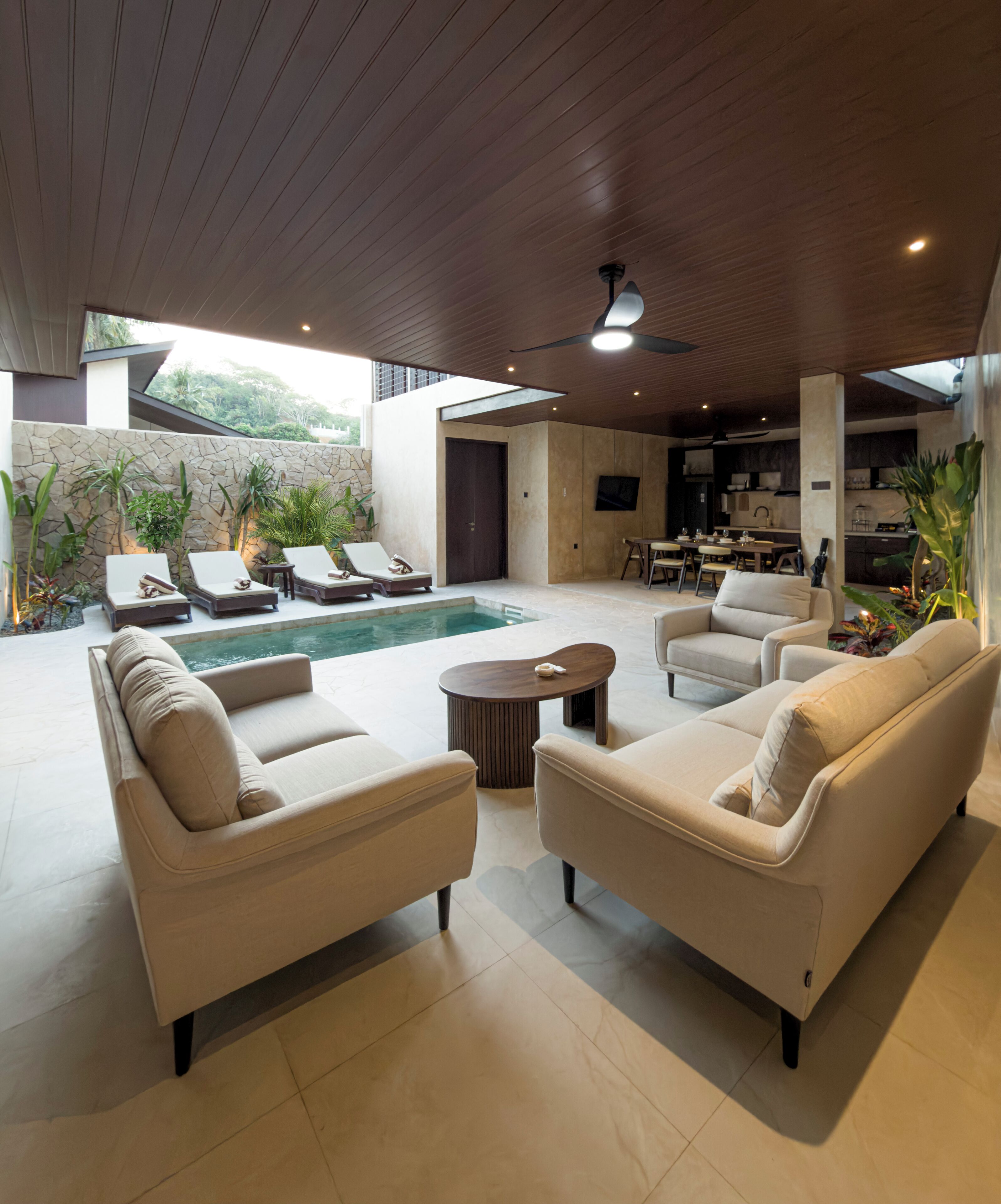 Un espacio exterior moderno con piscina, sillas de descanso, sofás y comedor.