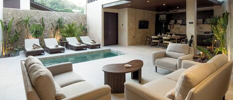 Un espacio exterior moderno con piscina, sillas de descanso, sofás y comedor.