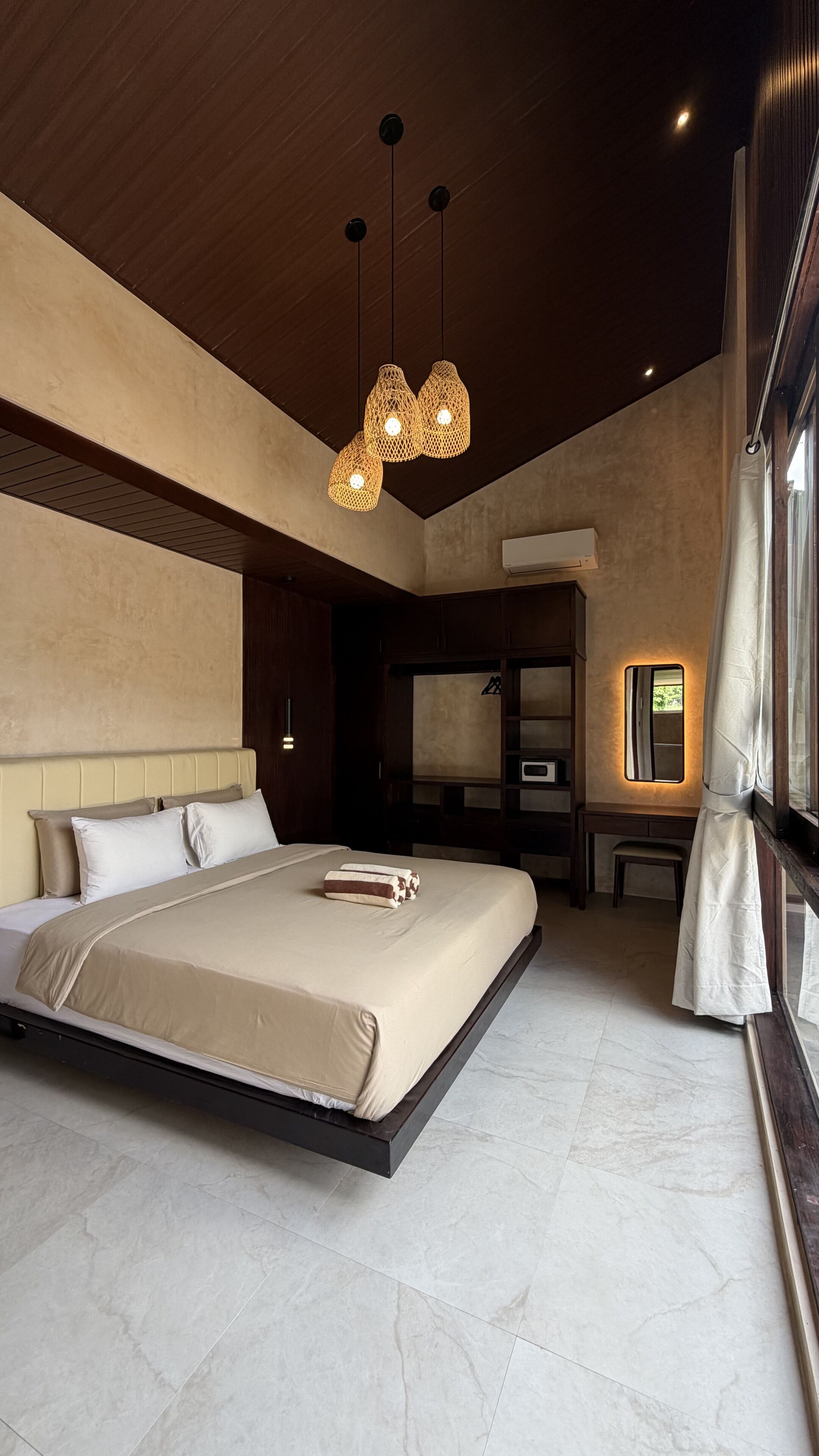 Une chambre moderne avec un grand lit, un plafond en bois et un luminaire suspendu.