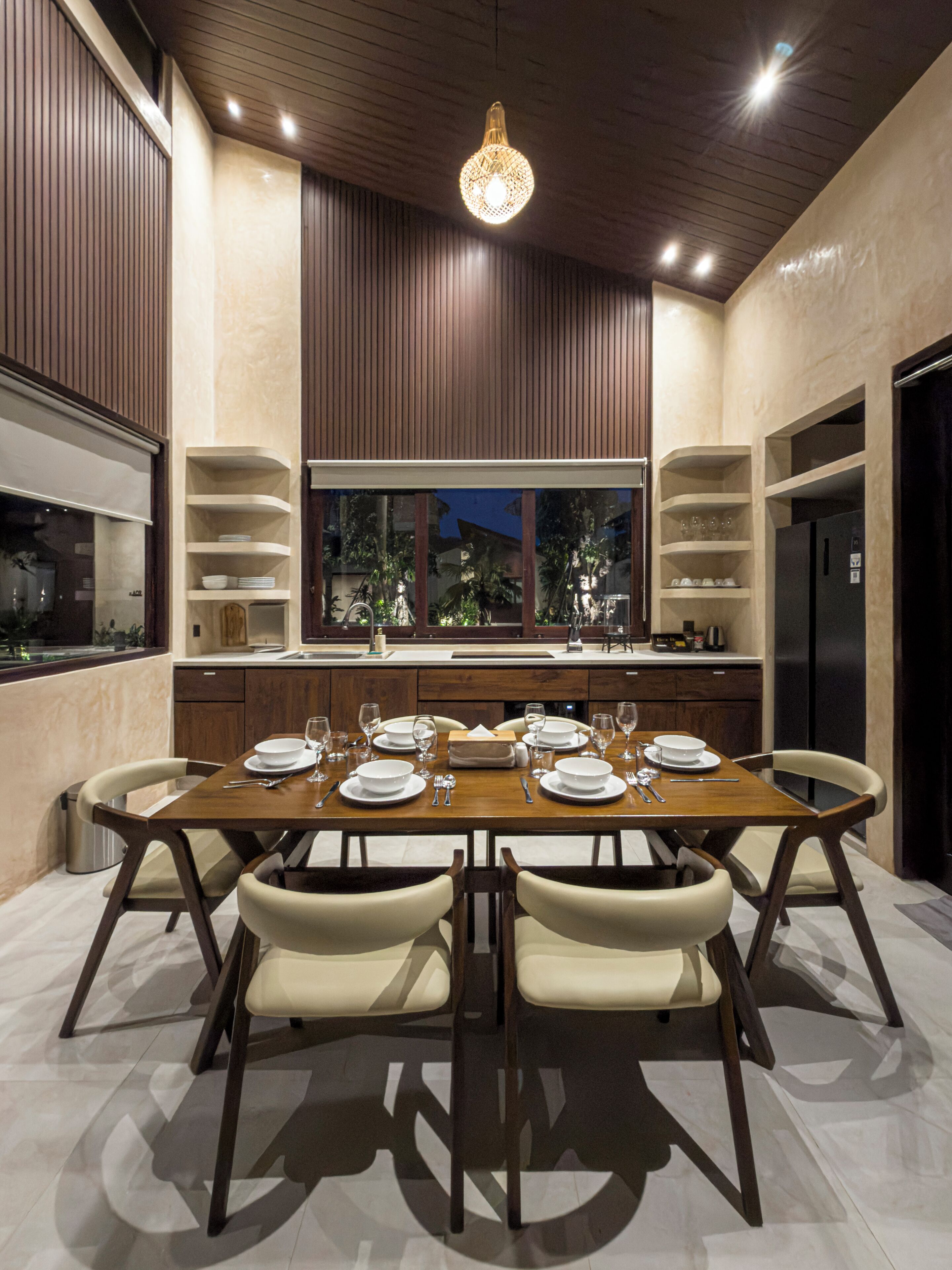 Un espace repas moderne avec une table en bois, dressée pour six personnes, entourée de chaises.