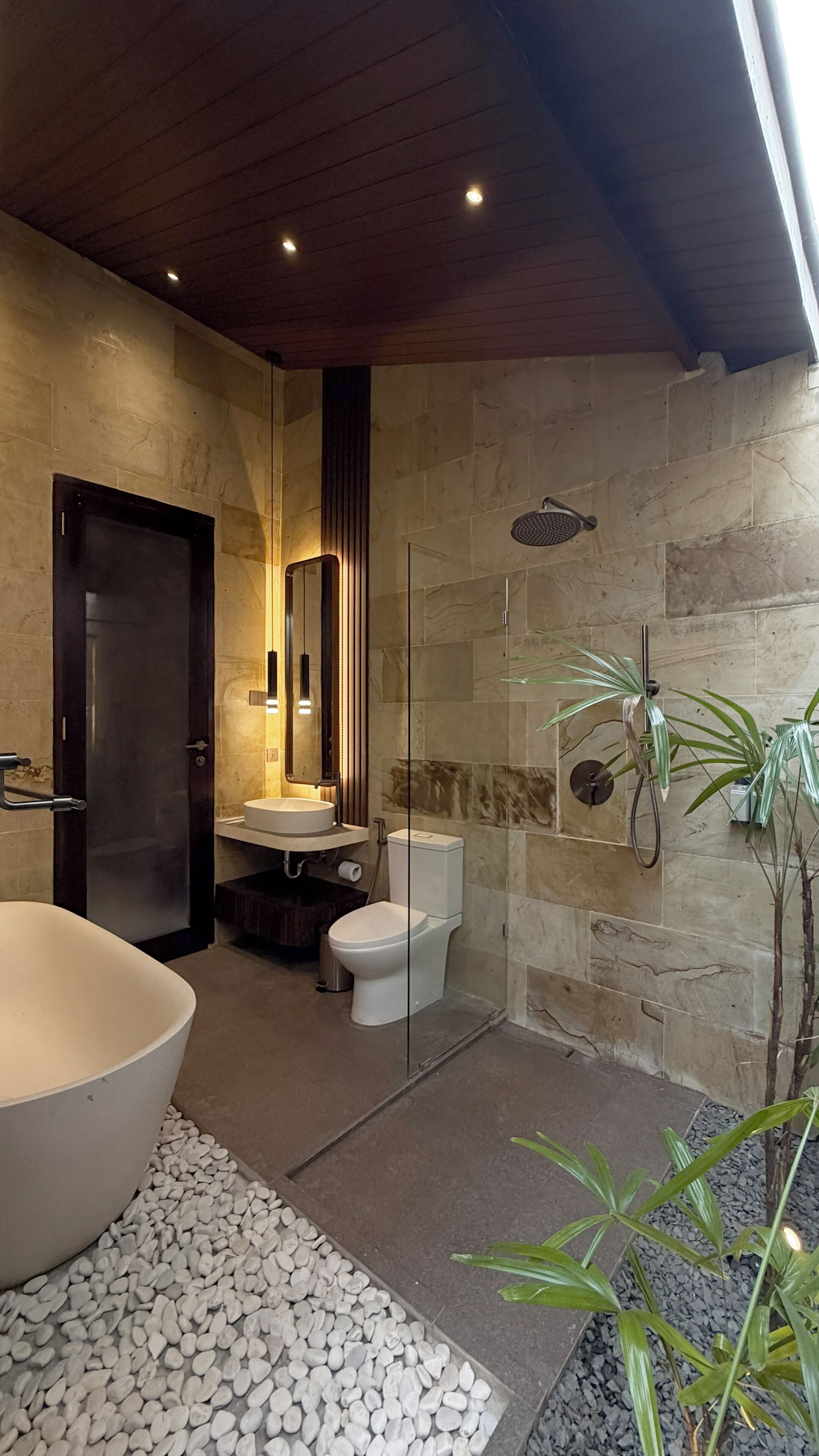 A modern bathroom with a large freestanding bathtub, a separate toilet, and a glass-enclosed shower area.
