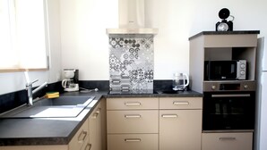 A modern kitchen with a sink, coffee maker, microwave, and oven. - Le Logis de Lucie ( 6 people) (Lys-Haut-Layon)