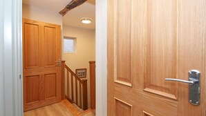 A wooden door with a metal handle, a wooden staircase with a handrail, and a small framed picture on the wall.