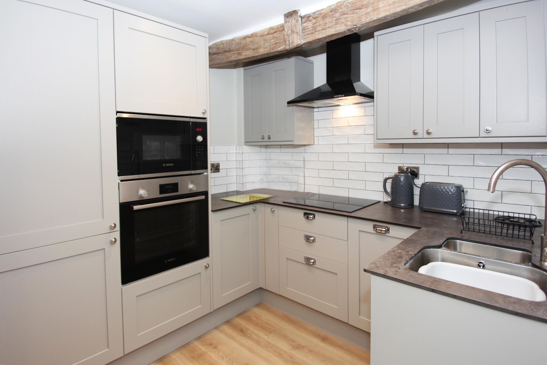 A kitchen with white cabinets, a Bosch oven, a toaster, and a sink.