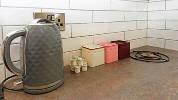 Una cocina con tetera, enchufe y algunos recipientes en la encimera.