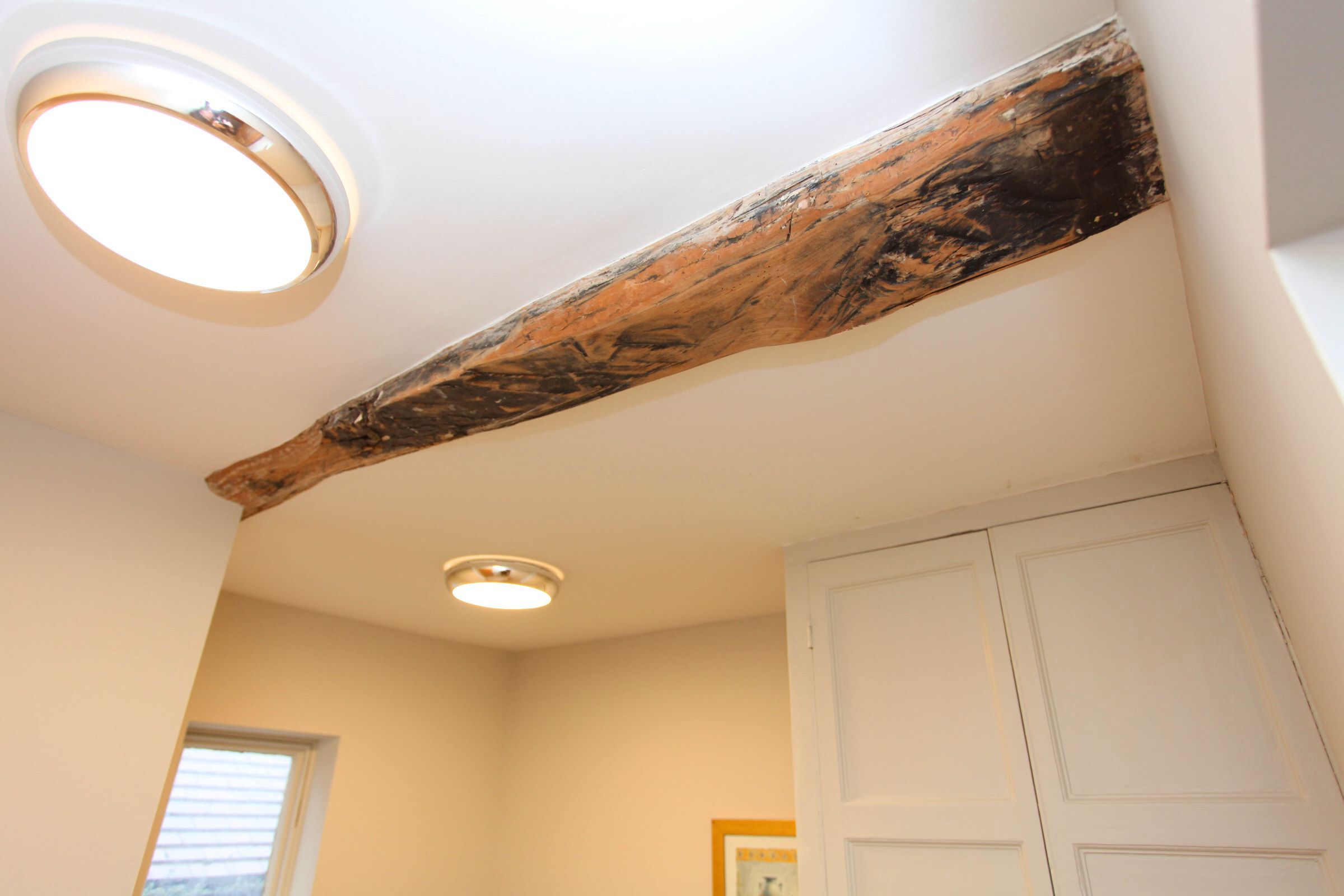 A room with a wooden beam ceiling, a white door, and a window with blinds.