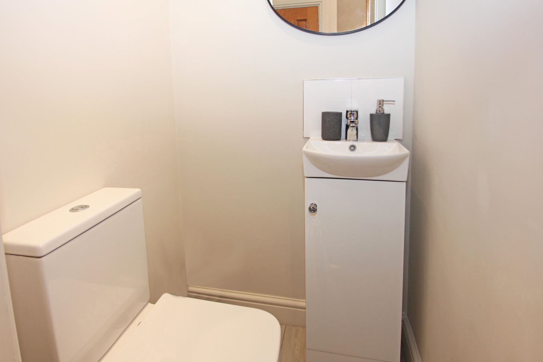 Un baño pequeño y blanco con inodoro, lavabo y espejo sobre el lavabo.
