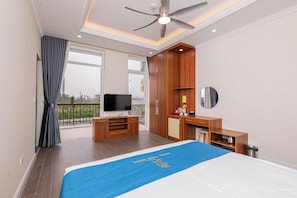 A hotel room with a bed, a desk, a television, and a balcony with a view. - Royal Louis Hotel (Hanoi)