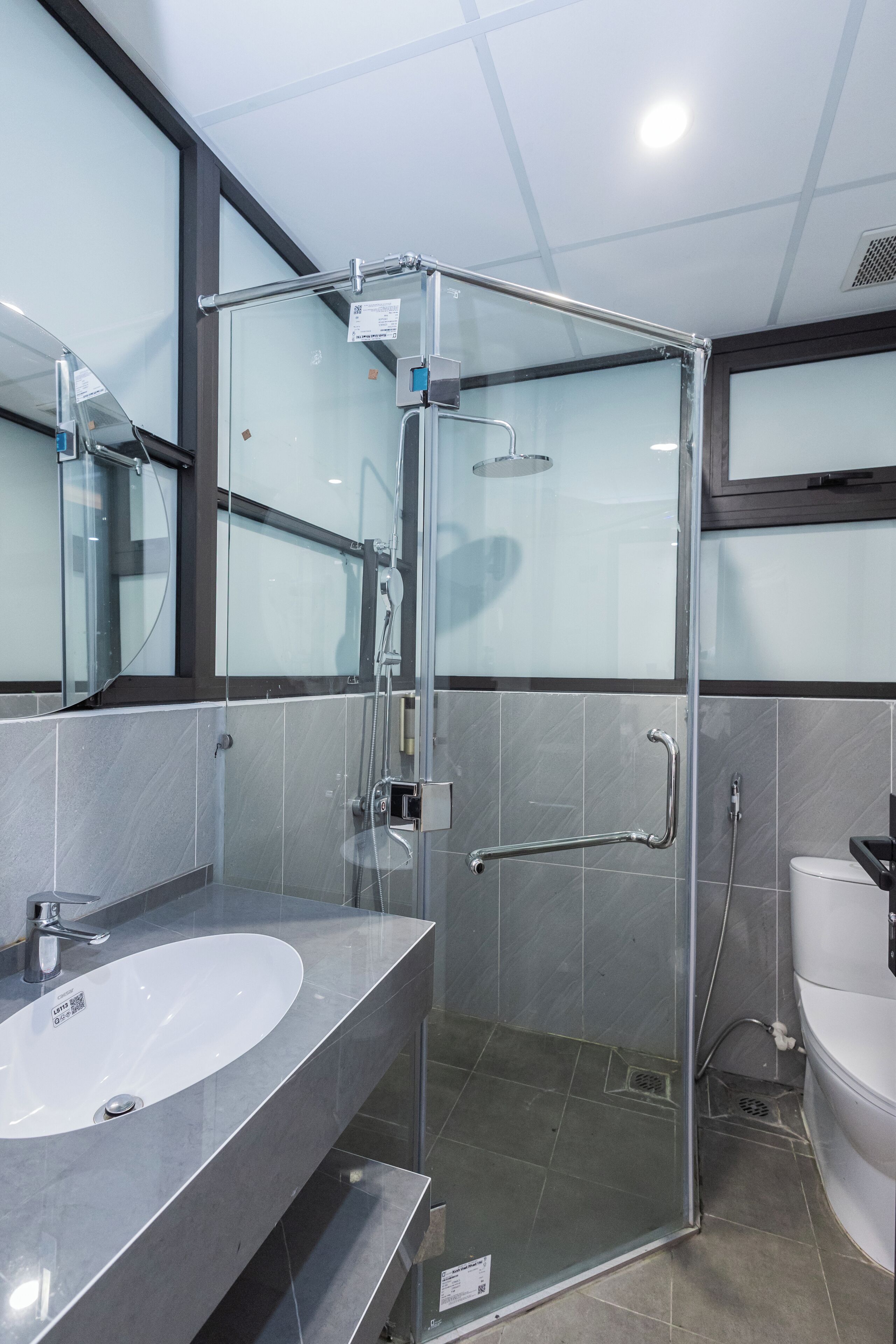 A modern bathroom with a glass-enclosed shower, a white sink, and a toilet.