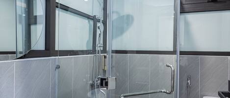 A modern bathroom with a glass-enclosed shower, a white sink, and a toilet.