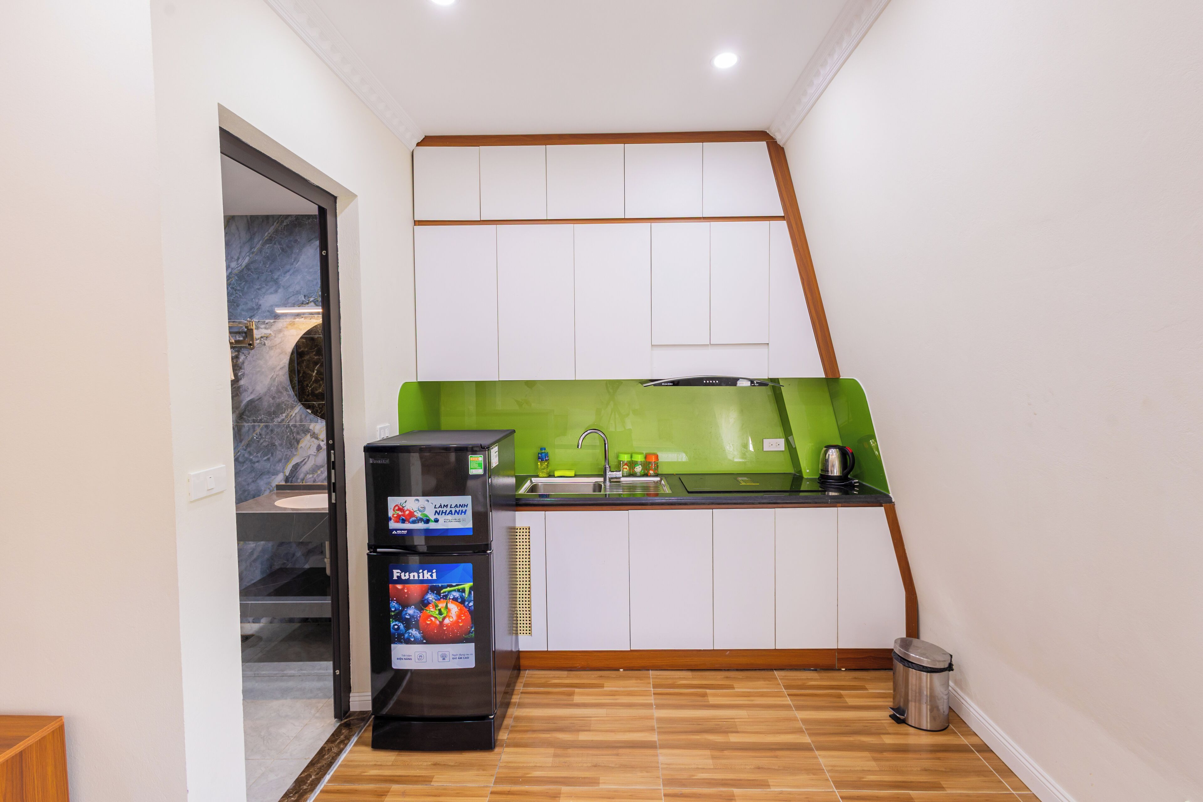 A compact kitchen with a built-in refrigerator, a sink, and a green backsplash.