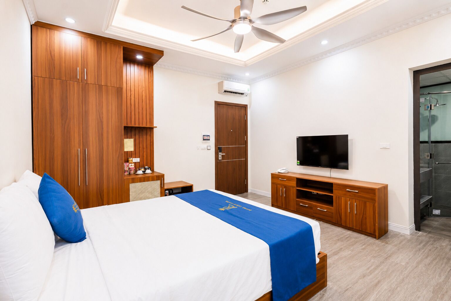 Een hotelkamer met een bed, een houten garderobe, een televisie en een douche.