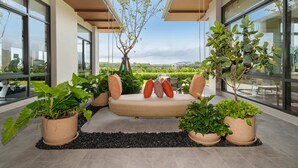 A modern interior with a sofa bed, potted plants, and large windows offering a view. - Canvas Condo New 2BR Near Beach 111-80 (Choeng Thale)