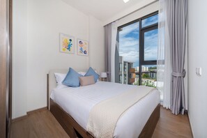 Een hotelkamer met een groot bed, uitzicht op de stad en twee kunstwerken aan de muur.