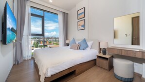 A modern hotel room with a large bed, a bedside table, a mirror, and a view of the city. - Canvas Condo New 2BR Near Beach 111-80 (Choeng Thale)