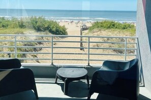 Ein Balkon mit Blick auf den Strand, ein kleiner Tisch und zwei Stühle.