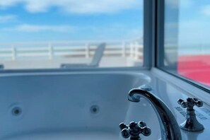 Un baño con un amplio ventanal, un lavamanos blanco y un grifo.