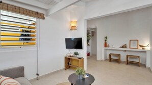 Un soggiorno moderno con televisore, divano, tavolino da caffè e un'area pranzo con una panca.