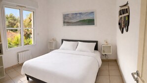 A bedroom with a bed, a window, a radiator, a painting, and a wall clock. - Villa private heated pool, 4 bikes, nearby beach, surf 🌊 (Moliets-et-Maa)