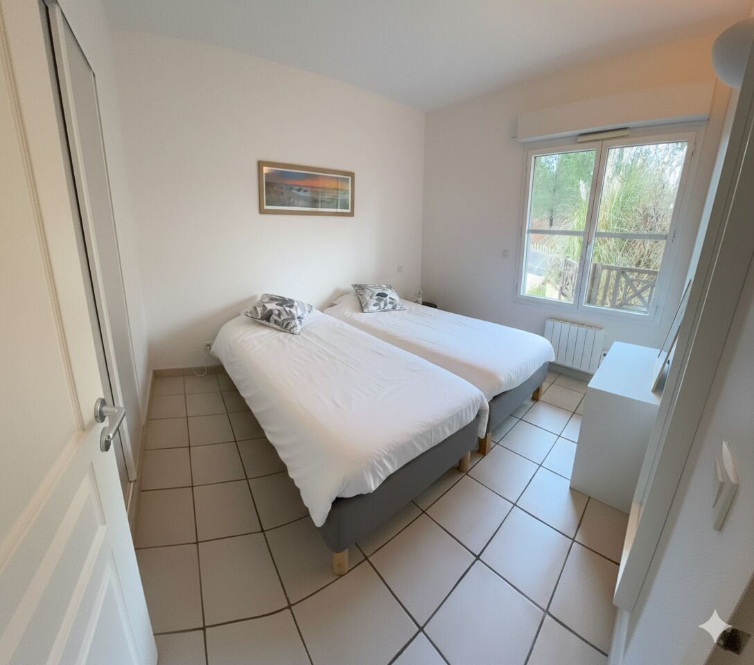 A room with two beds, a window with a view of trees, and a radiator.