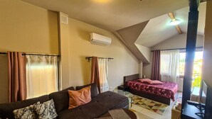 Een moderne woonkamer met een bank, een salontafel, een bed met bloemenbedekking en een televisie.