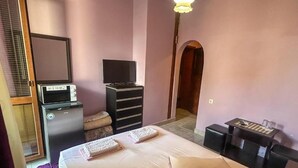 Een slaapkamer met een bed, een bureau, een televisie en een dressoir.