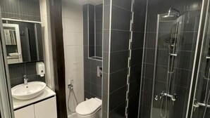 Een moderne badkamer met een douchecabine van glas, een wit wastafelmeubel en een toilet.