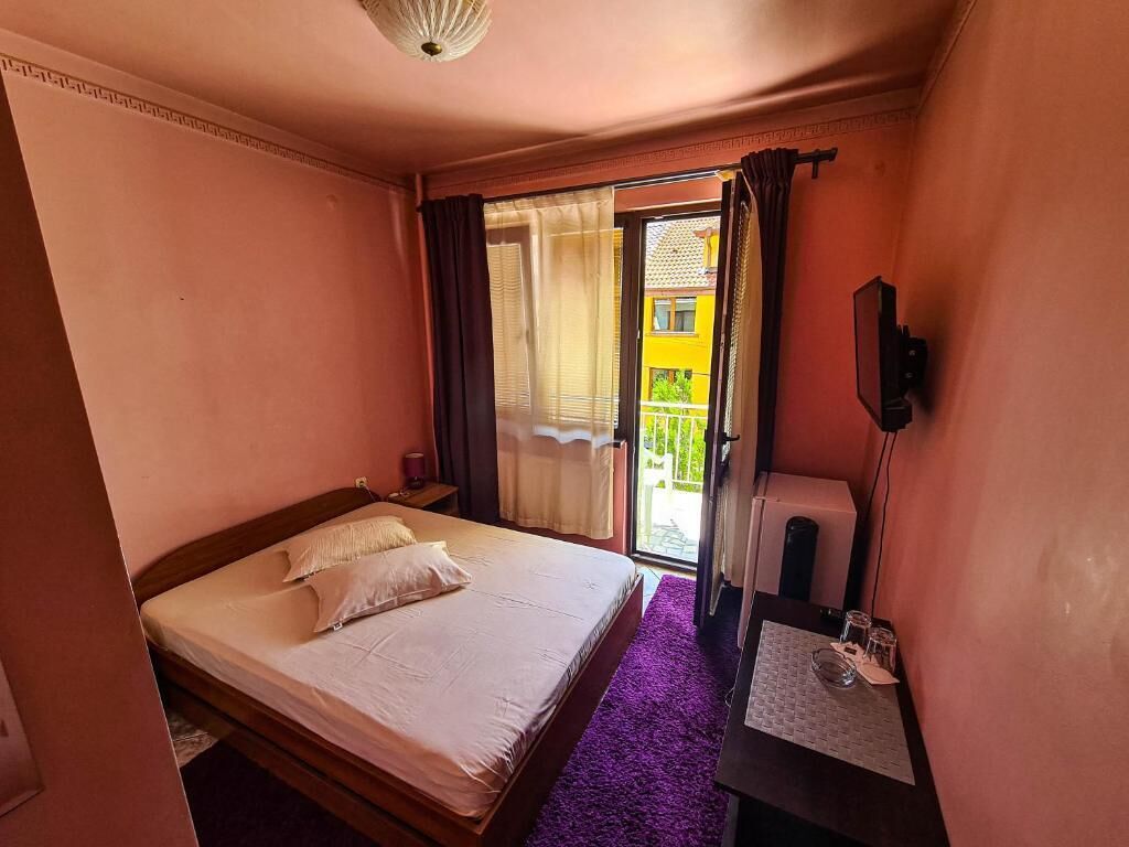 Un dormitorio con cama, una mesita con vasos, un espejo y vistas al exterior.