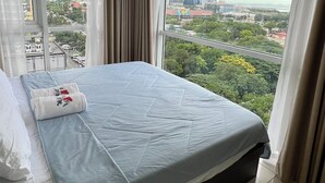 Ein Hotelzimmer mit einem großen Bett, Blick auf die Stadt und einer Klimaanlage.