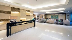 Eine geräumige Lobby mit Empfangsschalter, einer modernen Lounge und einem großen abstrakten Gemälde an der Wand.