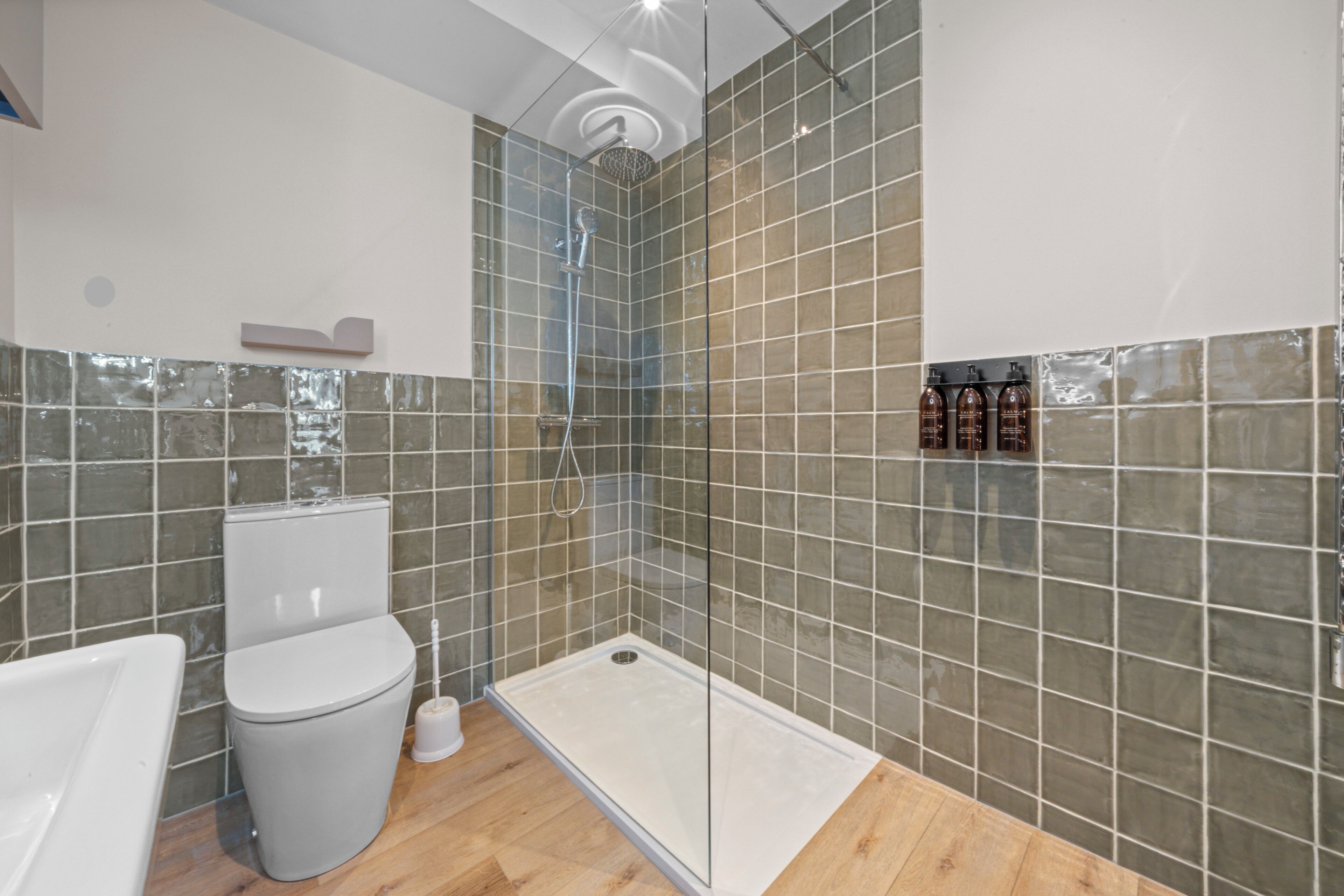 Un baño moderno con cabina de ducha de vidrio, inodoro y lavamanos.
