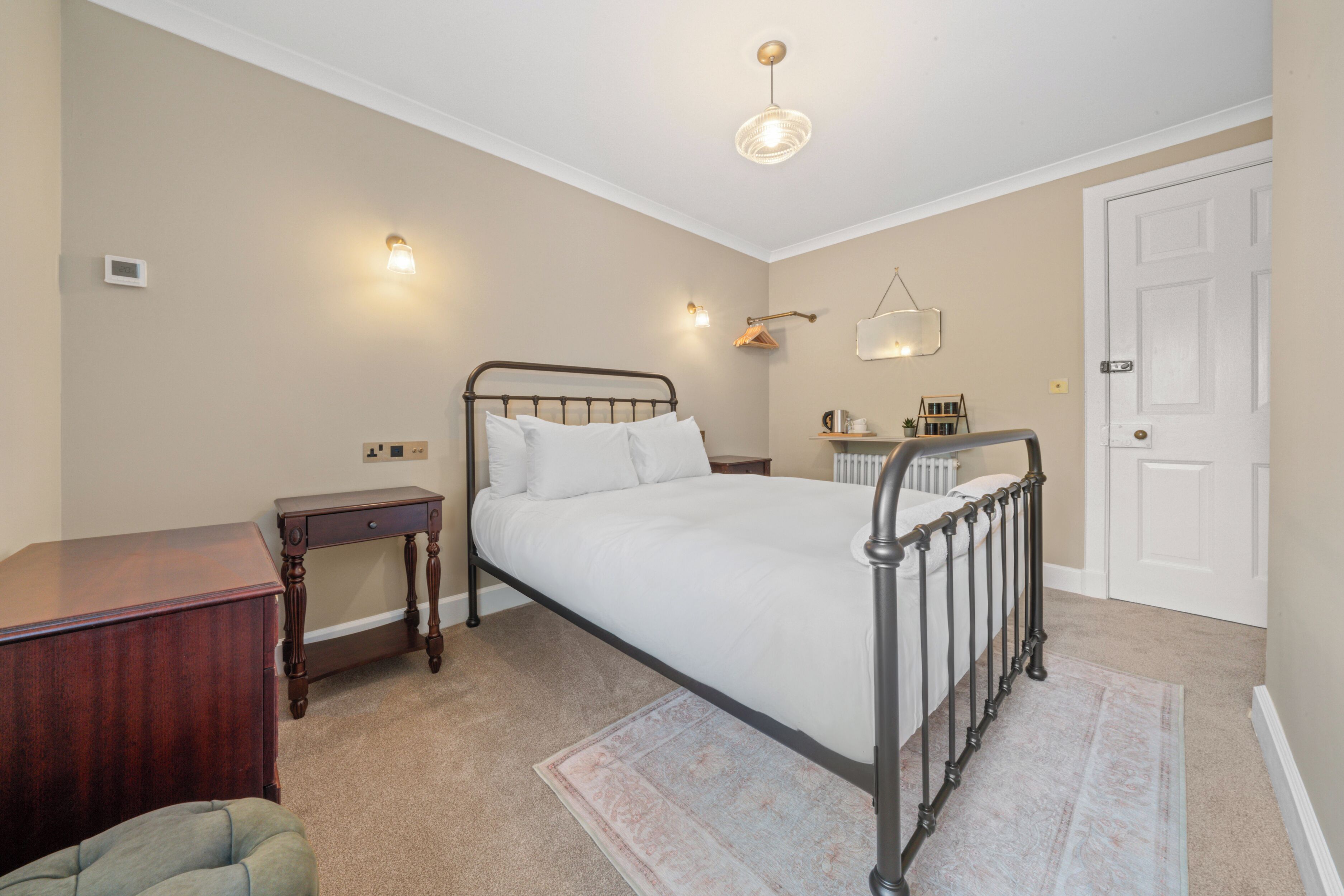 A bedroom with a bed, bedside table, nightstand, and a door.