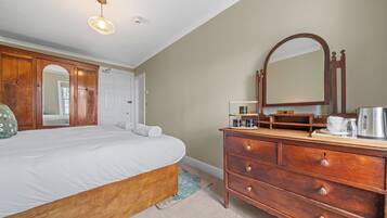 A bedroom with a wooden bed, a dresser with drawers, a mirror, and a ceiling light fixture.