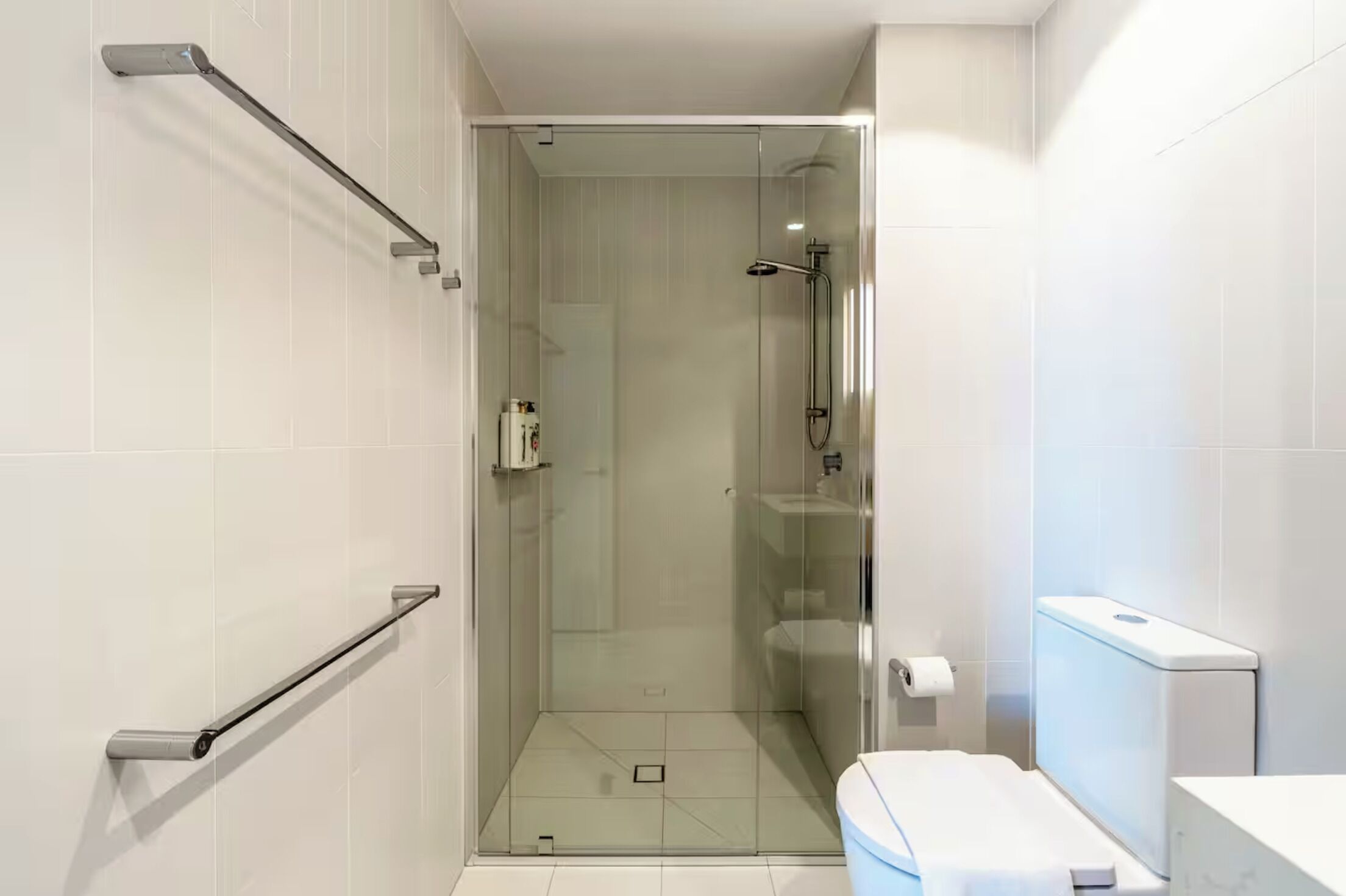 A modern bathroom with a glass shower enclosure, a toilet, and a sink.
