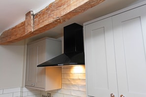 A kitchen with white cabinets, a black range hood, exposed wooden beams, and a tiled backsplash. - St John’s Hill - 2 Bedroom Apartment (Shrewsbury)