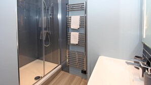 Een moderne badkamer met een douche met glazen wand, een handdoekhouder en een witte wasbak.