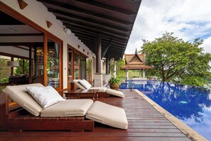 Une terrasse en bois avec des chaises longues et une piscine.