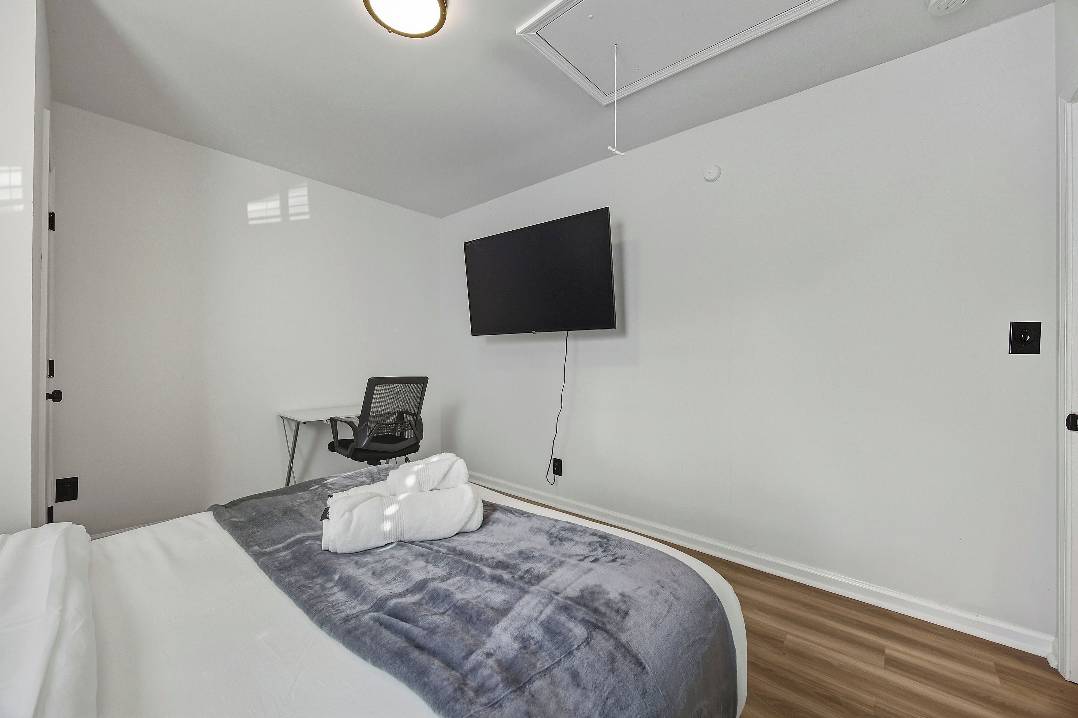 Habitación de hotel moderna con una cama, un escritorio y un televisor de pantalla plana montado en la pared.