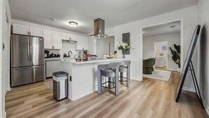 A modern kitchen with stainless steel appliances, a central island with bar stools, and a clean, minimalist design. - Charming West End House-comfort and Convenience in Atlanta (Atlanta)