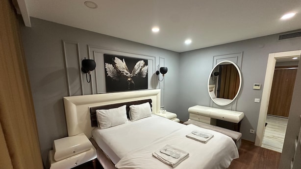 Ein modernes Hotelzimmer mit einem großen Bett, Nachttischen, einem Schminktisch mit Spiegel und einem Wandbild.