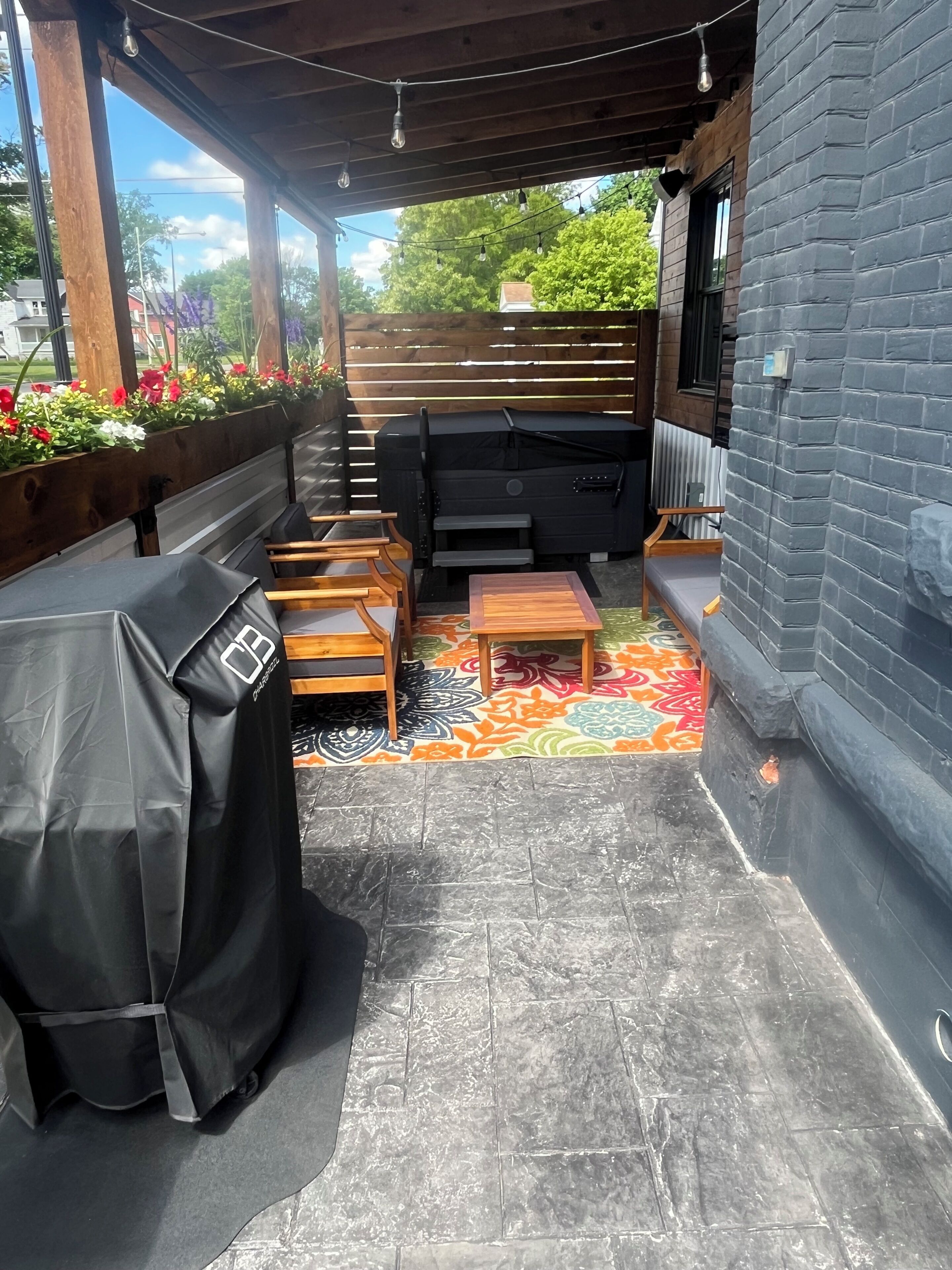 An outdoor patio with a barbecue grill, seating area, and a patterned rug.