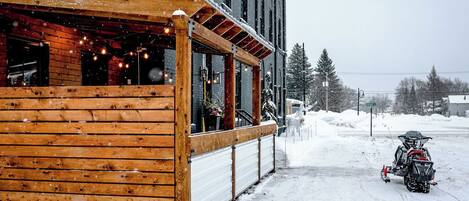 A wooden building with a covered outdoor area and a snow-covered street.