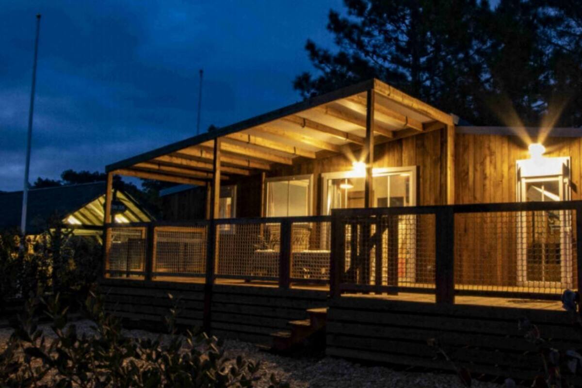 A wooden cabin with a covered porch and a fenced deck area.