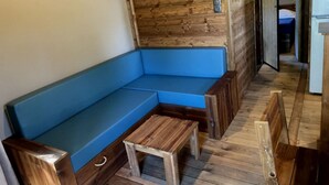 Interior de madera con un banco acolchado azul y una pequeña mesa de madera.